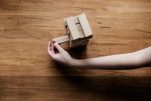 A hand playing jenga, the game where you build a tower from wooden bricks.